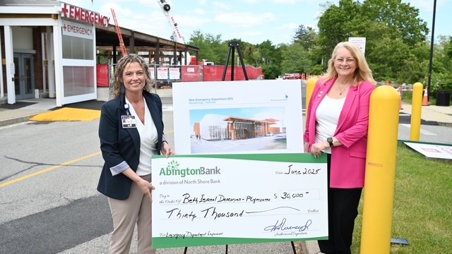 A bank employee holds a giant check for the donation to Beth Israel Deaconess Hospital.