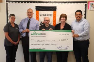 A group of people standing together holding a giant check for a donation