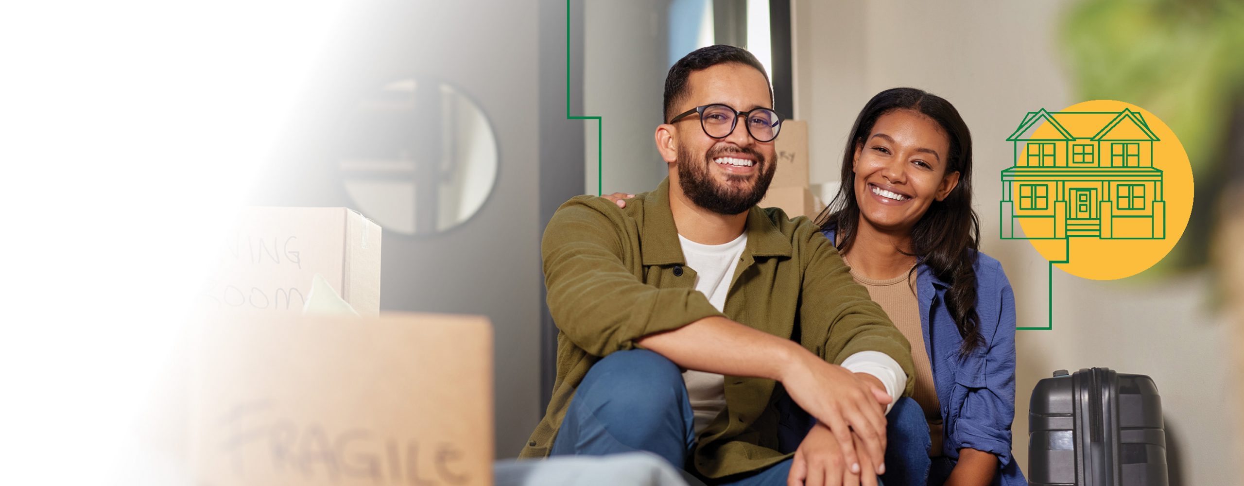 A couple sitting down next to a suitcase surrounded by moving furniture.