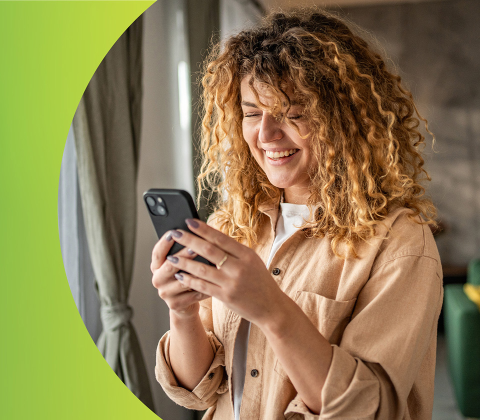 A woman smiling and looking down at her phone